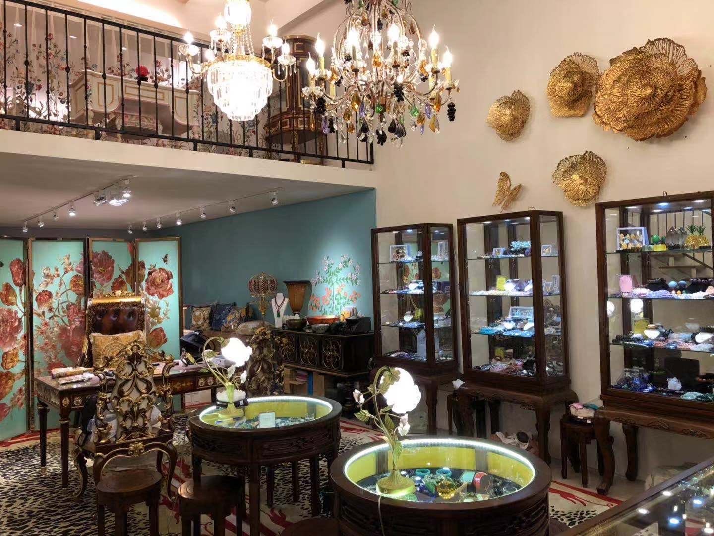 台北門市店內：水晶吊燈下的木質玻璃展示櫃與發光圓形展示桌