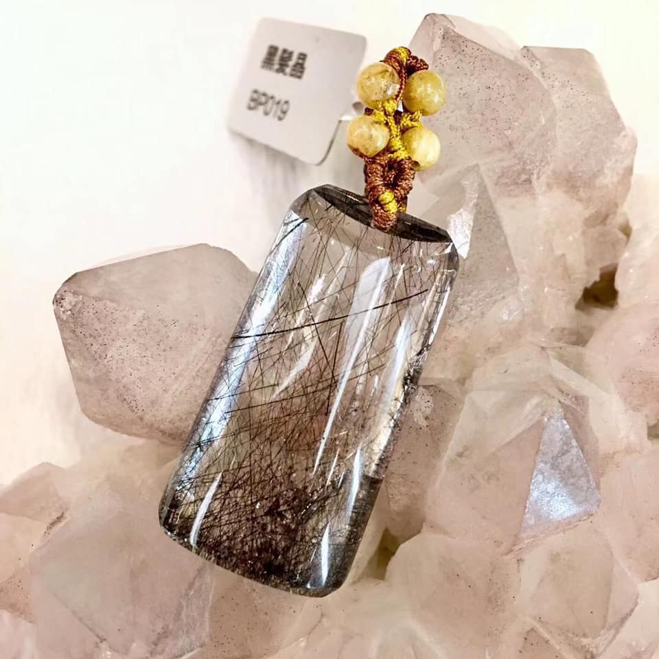粉晶簇前的黑髮晶吊墜