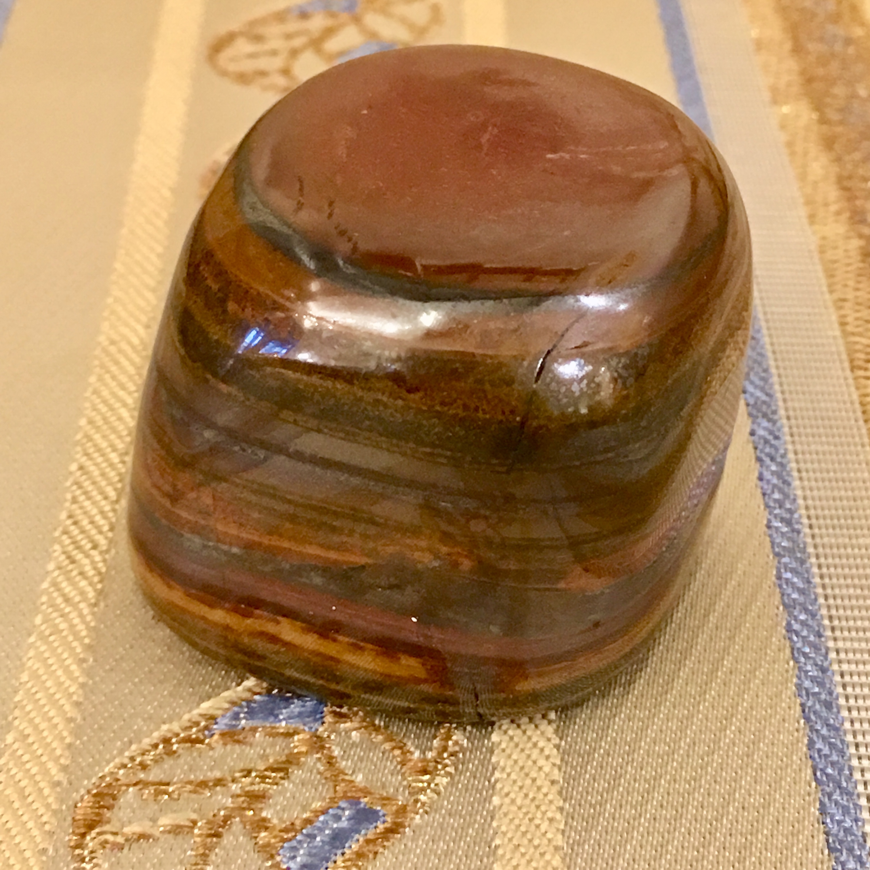 金色織紋布面上的方形虎眼石擺件,可見層層金棕色光澤紋理